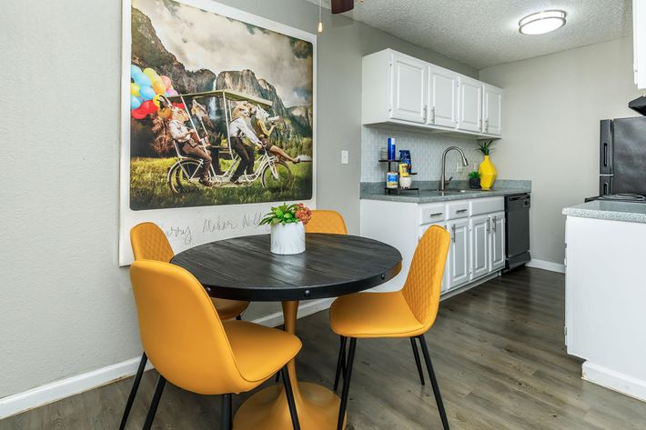 a kitchen with a table and chairs and a yellow chair at The Orbit Apartments